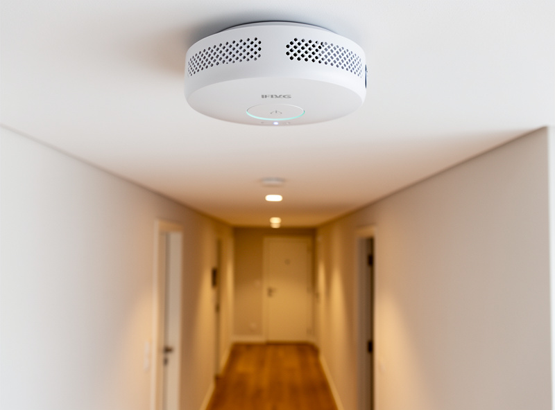 Smart smoke detector installed on hallway ceiling in modern home
