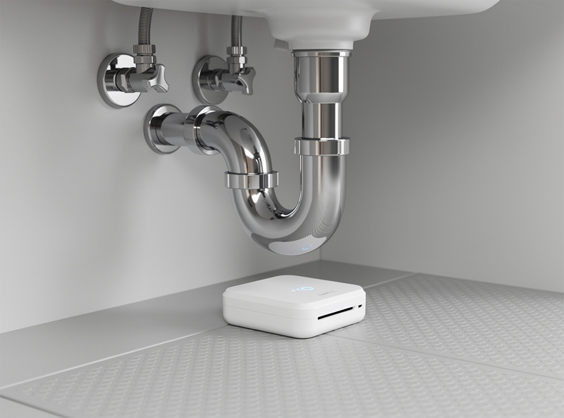 Smart water leak detector installed under bathroom sink near plumbing pipes