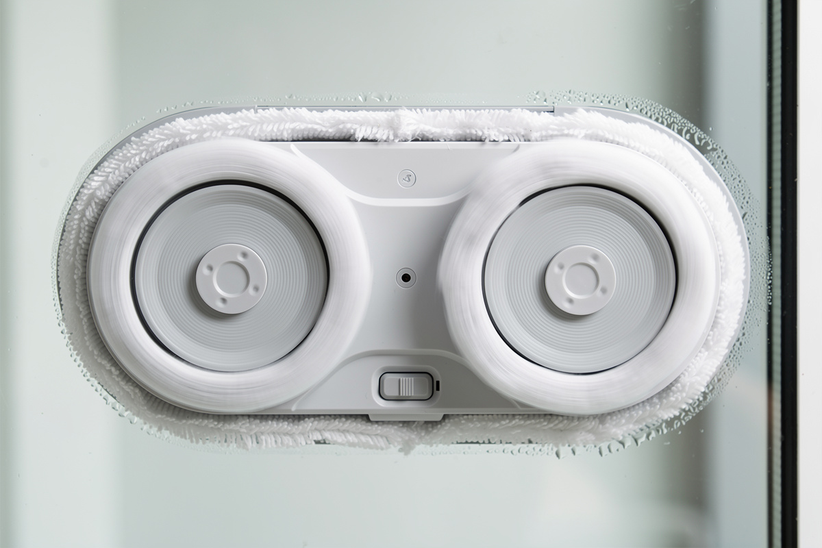 Close-up of window cleaning robot underside showing spinning microfiber pads and suction ring on glass