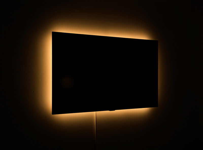 A TV with a warm bias light glowing behind it in a darkened home theater