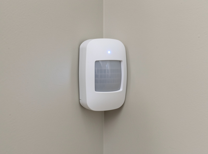 A motion sensor mounted on a wall with a smart home dashboard showing its last-seen status
