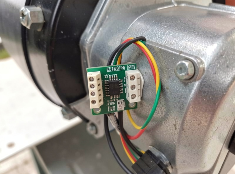 Small ESPHome garage door control board wired to a garage opener motor unit on the ceiling
