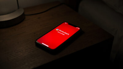 Phone on a nightstand at night glowing with an urgent home leak alert