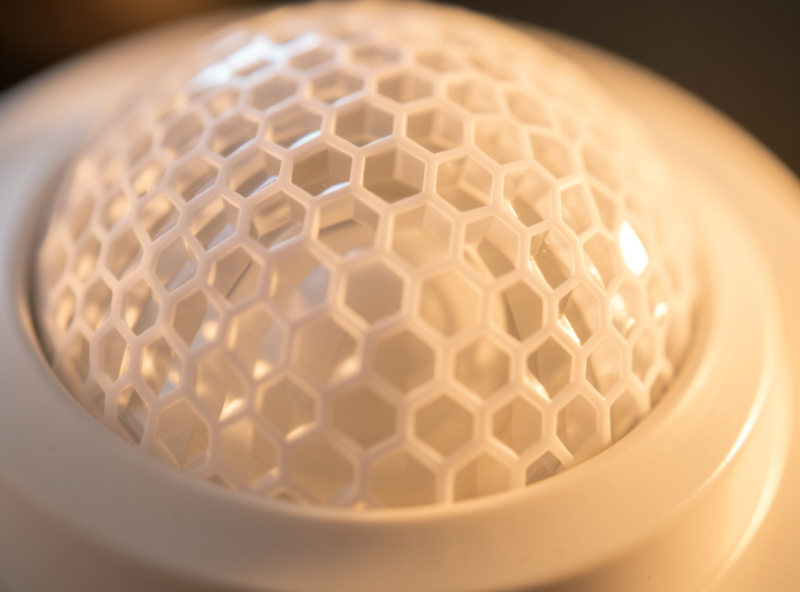 Macro detail of a white honeycomb Fresnel lens on a PIR motion sensor dome