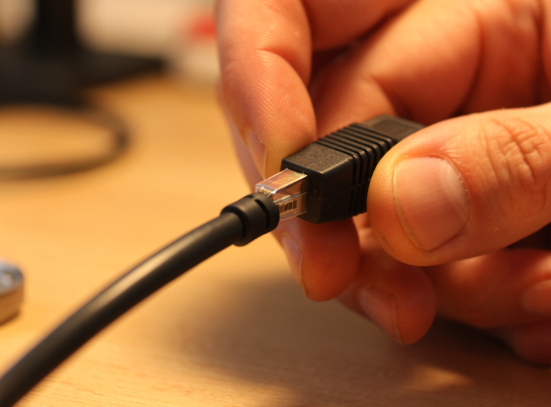 Close-up of an ethernet cable being plugged into a camera pigtail connector